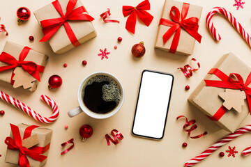 top view of smart phone with hot cup of coffee. Christmas decoration on colored background