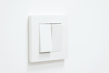 White light switch on white wall. One part of switch is turned on, the other is turned off
