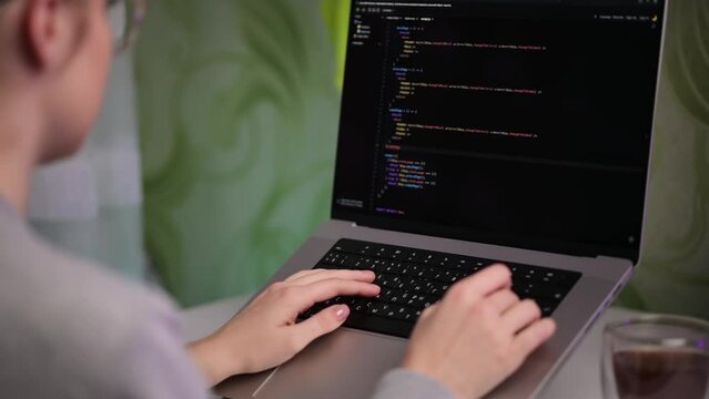 A girl programmer works at home. A woman is writing code for a program or website on a laptop. innovative technologies