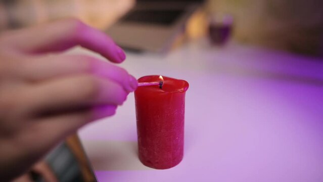 A girl lights a candle near her workplace. Creating a romantic and cozy atmosphere. Valentine's day. Saving electricity