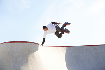 Energetic man on roller skates in motion at modern roller skate park. Roller skater doing dangerous...