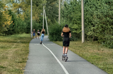 A young woman is riding on the electric scooter in a summer park.