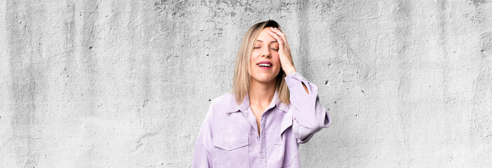 blonde adult woman laughing and slapping forehead like saying d’oh! I forgot or that was a stupid...