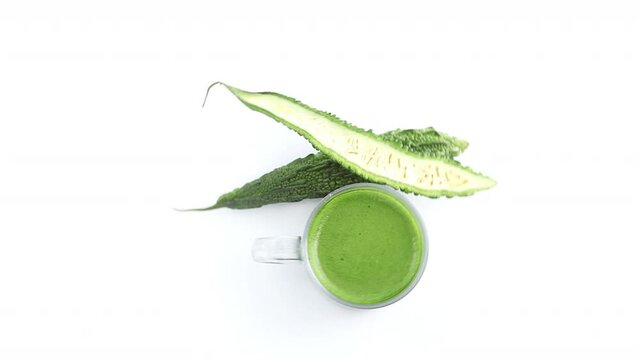 sliced bitter gourd and biter gourd juice, paste in white background rotating top shot
