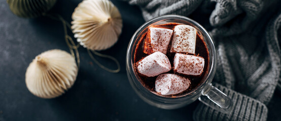 Banner image for design, web page. Glass with hot chocolate with marshmallow on dark blue background. Top view