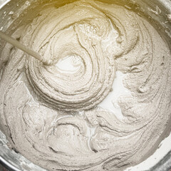 mixing cement adhesive with a mixer in a bucket close-up, texture of a mixed mortar