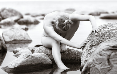 Nude woman enjoying nature among stones by the sea