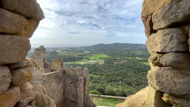 Tourism medieval ruined castle in Spain seen from a rock window towards the rest of the castle with a cultivated field in the background