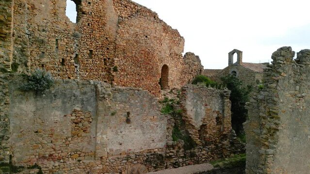 Ruined castle in Europe aerial footage cinematic medieval era Sliding to the left revealing a small church inside Palafolls Barcelona