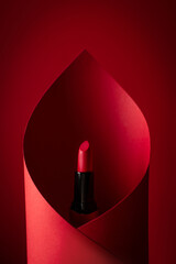 red lipstick wrapped in red paper on a red background - obrazy, fototapety, plakaty