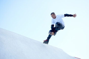 Energetic man on roller skates in motion at modern roller skate park. Roller skater doing dangerous...