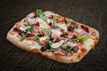 Pizza Carbonara with bacon, chanterelles, arugula, mozzarella, parmesan, pesto. Roman pizza rectangular on wood background