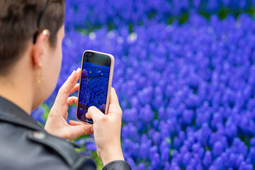 Smartphone, mobile phone in hands of abstract girl closeup. Taking flowers photo, video. Modern technology, spring