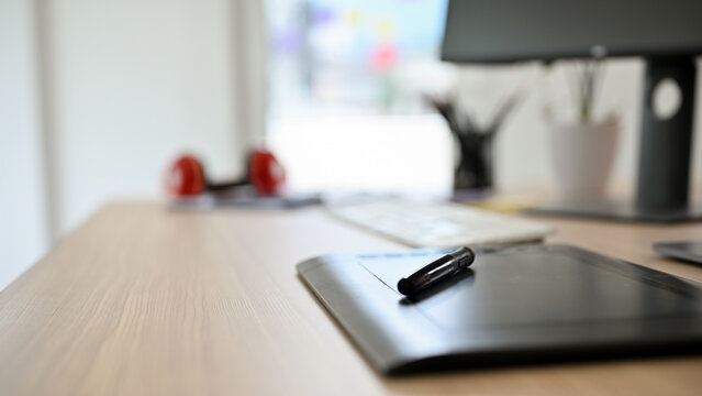 Close-up image, A modern stylus tablet and stylus pen on wooden office desk.