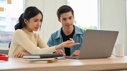 Two professional young Asian business startup workers focused on working together