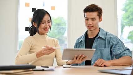 Two young Asian female and male marketing workers discussing on their project.