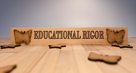 Educational Rigor written on wooden surface. Wooden butterflies and white background. Education and...
