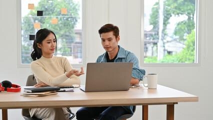 Professional Asian male and female employees focused on their project, working together