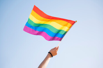 Hand of a woman waving an LGBT pride flag.
