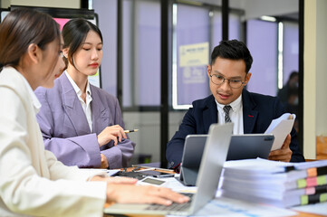 Smart millennial Asian businessman explaining and sharing his ideas to his team