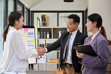 Professional adult Asian businessman shaking hand with a female business partner