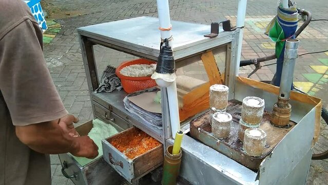 traveling "kue putu" traders, are a type of traditional Indonesian snack in the form of cakes filled with brown sugar, wrapped with grated coconut, and coarse grained rice flour.