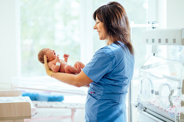 Nurse with newborn baby in postpartum ward. Maternity hospital, doctor and nurse neonatologist.