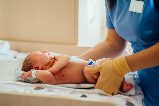 Adorable Newborn Baby 3 Day Old Girl In Diaper Check Up Examines By Unrecognizable Pediatrician Doctor In Hospital.