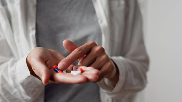 Choosing a pill with the index finger The girl holds bunch of bright-colored pills in the palm of her hand choosing the right painkiller pill for her head, taking medical drugs in the form of capsules
