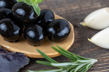 olives with spices and rosemary in a wooden spoon