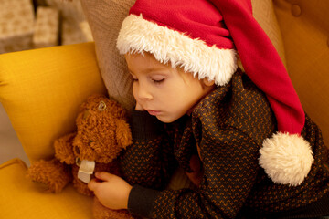 Cute child, boy, sleeping in yellow armchair in a decorated room for Christmas