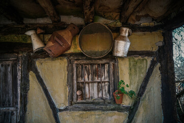 Old milk churns, tin bucket for milk, in a rustic village in Spain, Vintage style, window with old stone and wood background