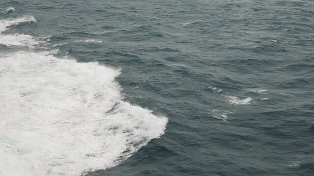 Storm. High waves. White foam on wind. Side view low on water. Wind breaks waves. Splashes