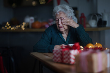 Unhappy senior woman sitting alone and crying during Christmas Eve.Concept of solitude senior and...