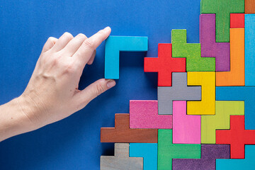 Concept of decision making process. Logical tasks. Hand holding wooden puzzle element. Hand sets...
