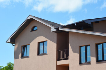 Modern house with asphalt shingles roof,  balcony, rain gutter pipeline and soffit boards outdoors.