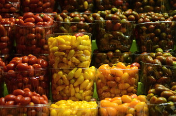 Showcase with cherry tomatoes at the Tel Aviv market. Yellow, green and red small tomatoes in plastic boxes