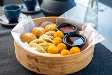 Oriental dumplings and shrimps in batter served  in a bamboo basket