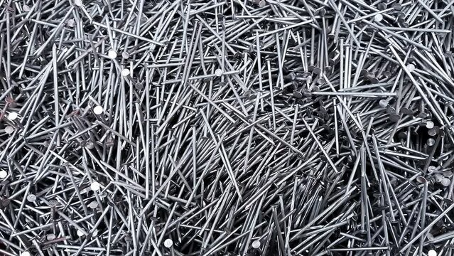 A lot of long metal nails top view close-up. Steel texture. Concept of repair, building or a hardware shop background. Heap of sharp gray color objects for a fixing build material. Moving footage.