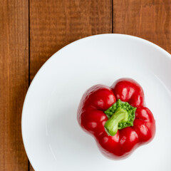 Ripe bell pepper on a white plate. A plate with vegetables on the table. Suitable for vegetarians. Diet food.