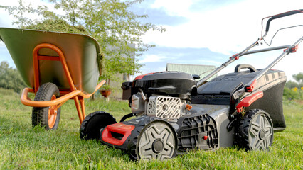 Fototapeta premium Lawn mover on green grass in modern garden. Machine for cutting lawns.