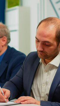 Businessman reading paper document, discussing contract with confident partner, signing investment papers. Executive director meeting shareholders in start up office, making satisfactorily agreement.