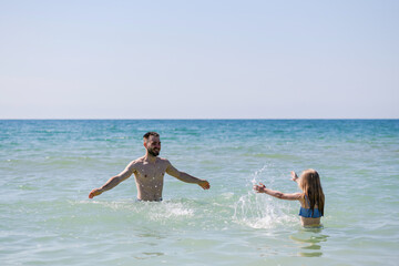 Young father swim with daughter at sea