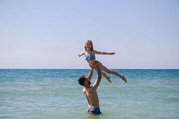 Young father hold up daughter child gymnast girl under sea water, happy family vacation leisure and activity