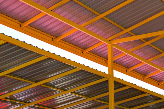 Metal sheet rooftop with yellow painted iron construction, view from inside the construction, worm eye view.
