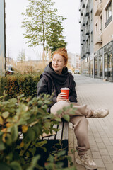 Red-haired girl drinking coffee on the street