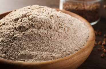 Fototapeta na wymiar Bowl of buckwheat flour on wooden table, closeup
