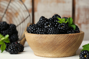 Bowl with fresh ripe blackberries on white wooden table, closeup