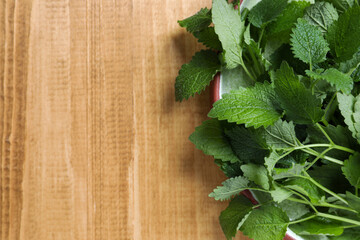 Fresh lemon balm on wooden table, top view. Space for text