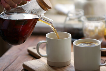 Pouring delicious tea into cup on wooden table, closeup